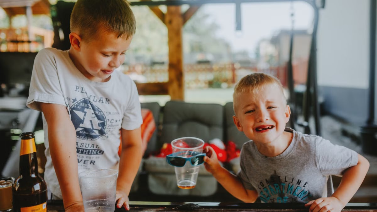 Two young boys having fun outdoors with drinks and laughter.