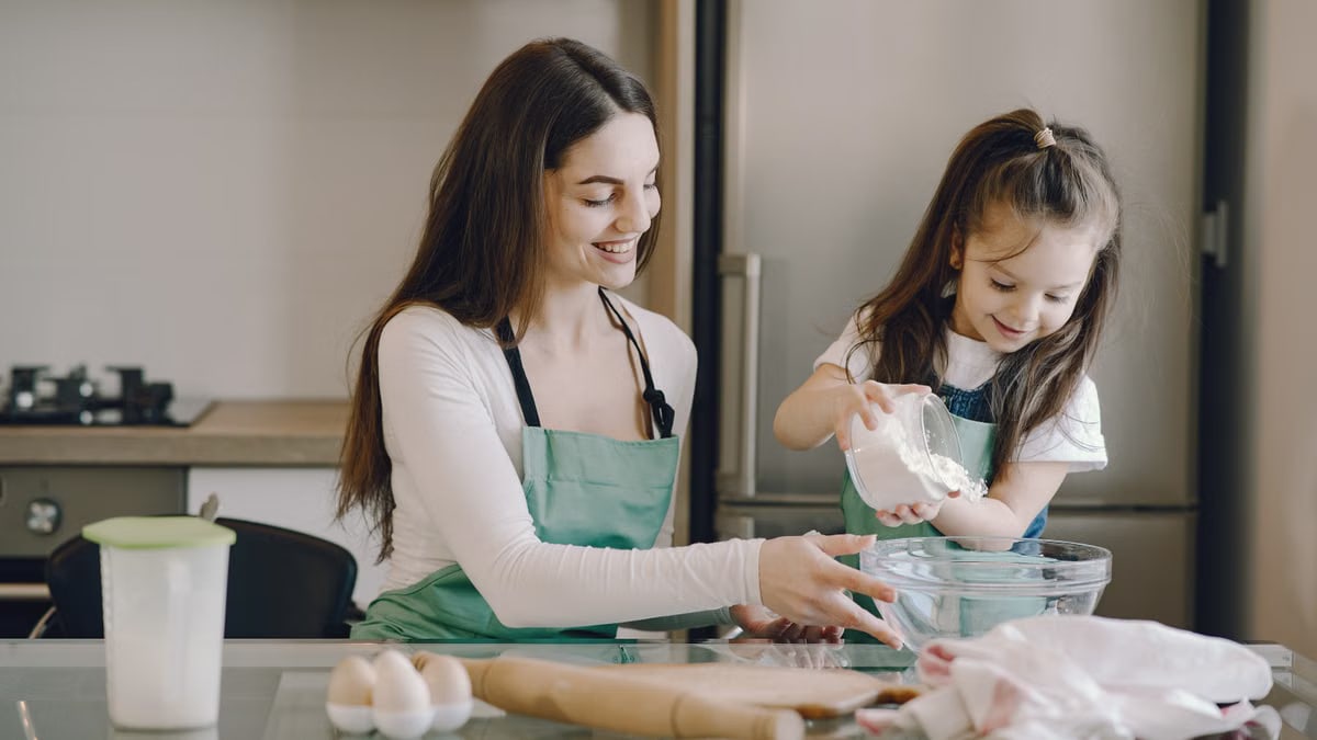 A joyful mother and daughter bonding while baking in the kitchen, smiling and enjoying the activity.